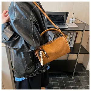 Detail of vintage brown suede cylinder bag with stylish colorful beaded tassel accessory