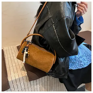 Detail of a brown suede cylinder bag featuring an ethnic wood bead tassel charm