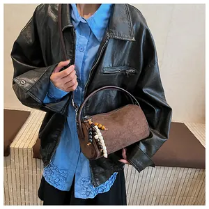 Detailed view of a vintage brown cylindrical underarm bag with wooden bead pendant