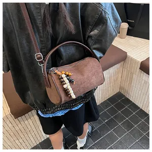Detail of brown frosted leather cylinder bag with wooden beads and curved handle