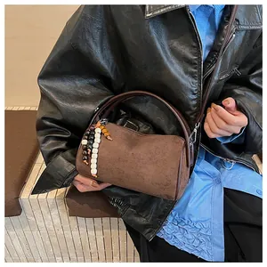Close-up of retro brown cylindrical bag with matte suede texture and beaded charm