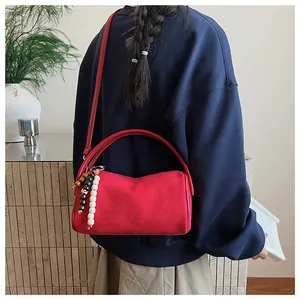 Detail of red cylindrical shoulder bag in matte finish with colorful wooden beads charm