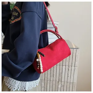 Detail of red frosted retro cylinder bag with beaded charm and slim shoulder strap