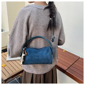 Detail of navy blue suede pillow bag with colorful wooden beads and thin shoulder strap