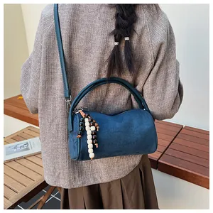 Detail of navy blue frosted suede barrel bag with wooden bead tassel and double handles