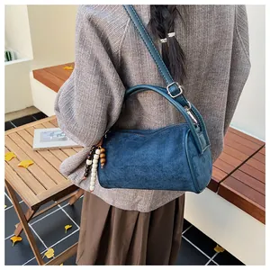 Detail of dark blue vintage Boston bag with wooden bead tassel in autumn outdoor setting