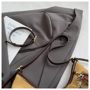 Détail du sac bandoulière en daim marron avec boucles dorées et fine lanière en cuir chic