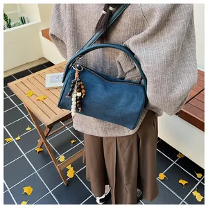 Detail view of navy suede barrel bag with wooden bead charm and autumn aesthetic setup