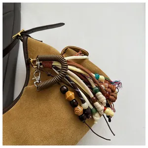 Détail du sac en daim avec cordes tissées bohèmes colorées et breloques en perles