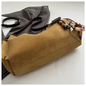 Détail du sac cabas en daim camel avec perles en bois bohèmes et glands tressés