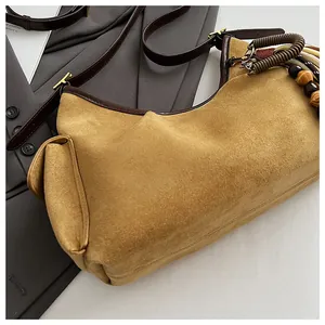 Détail du sac hobo en daim camel avec garniture en cuir marron et pendentif en perles