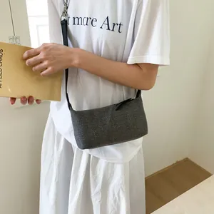 Minimalist grey woven crossbody bag with black strap shown on model for daily styling