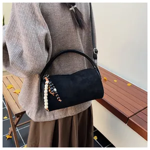 Close-up of vintage black matte baguette bag with wooden bead charm in an autumn setting