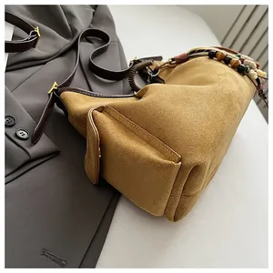 Détail du sac à main en daim jaune moutarde avec bandoulière ornée de perles ethniques