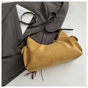 Détail du sac à main en daim jaune avec bordure en cuir marron et poches latérales