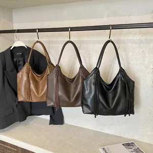 Tres bolsos tote vintage con borlas en colores caramelo, marrón oscuro y negro en un estante