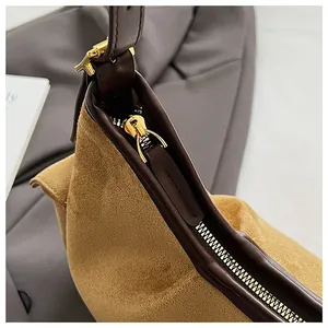 Vue détaillée de la fermeture éclair dorée et de la texture en daim de ce sac à main