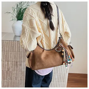 Gros plan d'un sac hobo en daim marron avec texture plissée et pompons à perles
