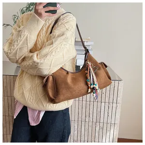 Détail du sac hobo en daim caramel avec perles colorées et pompon sur la bandoulière