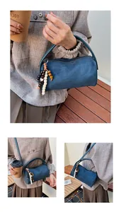 Detailed view of blue matte suede boston bag with ethnic wooden bead tassel decoration