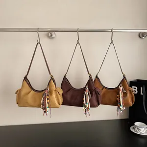 Trois sacs portés épaule en daim bohème aux tons terre avec des pompons colorés