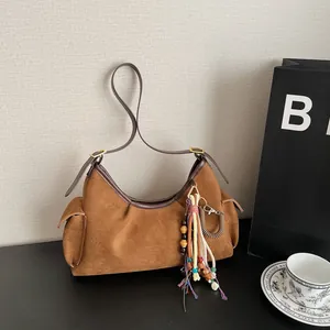 Sac à bandoulière rétro en daim marron avec poches latérales et pompon bohème chic