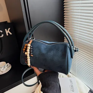 Deep blue suede cylindrical Boston bag with decorative wooden beads and shoulder strap