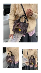 Detail of leopard print faux suede handbag with black leather handles and gold hardware