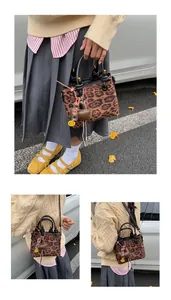 Detail of leopard print crossbody bag with heart charm and black top handle in outdoor setting