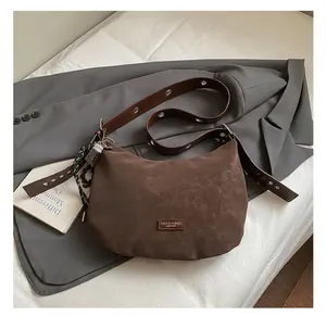 Detail of dark brown suede hobo bag with eyelet strap and metallic charms