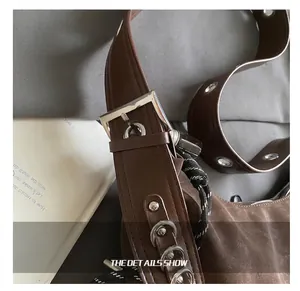 Detail of dark brown suede crossbody bag showing adjustable strap and silver buckle