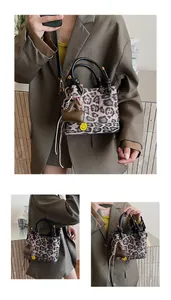 Detail view of leopard print crossbody bag with smiley face charm and round handle