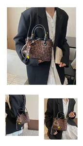 Detail of leopard print tote bag with black round handles and yellow smiley pendant charm