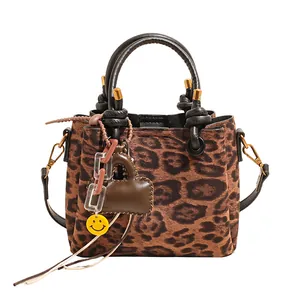 Macro shot of faux suede leopard print handbag with heart charm and smiley pendant