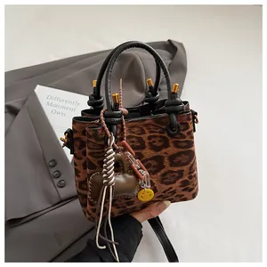 Detail of leopard print crossbody bag featuring gold hardware and smiley face charm