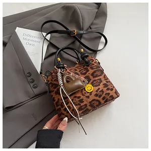 Detail of leopard print suede mini bag with black leather handles and chic charms