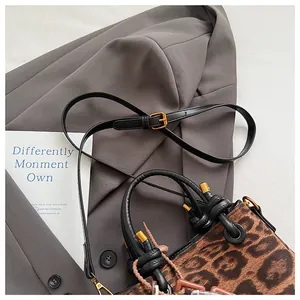 Detail of leopard print faux suede bag with twisted top handle and golden hardware