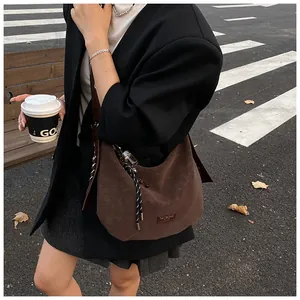Photo en extérieur d'un sac hobo marron rétro avec charme tissé et étiquette en cuir