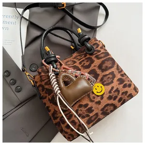 Detail of leopard print suede mini handbag with black round handle and heart charm pendant