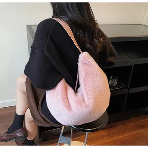 Détail du sac à main en peluche rose pâle porté à l'épaule pour le style hivernal