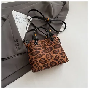 Close-up of leopard print handbag with matte gold hardware on a grey blazer