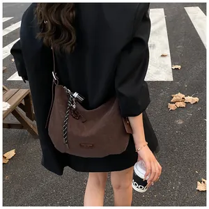 Détail du sac rétro marron foncé avec breloque en corde tressée et plaque en cuir