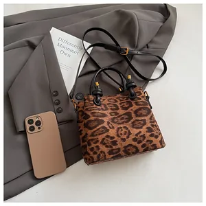 Leopard print faux suede crossbody bag displayed on a grey blazer with accessories