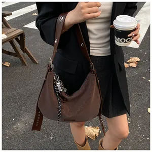 Détail du sac à bandoulière marron vintage avec œillets métalliques sur la sangle