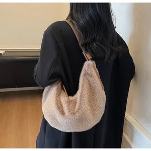 Détail du sac hobo en peluche marron clair avec bandoulière en cuir porté par un modèle