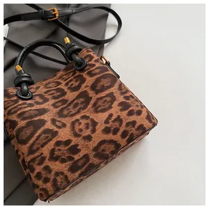 Macro detail of leopard print suede texture and bronze metal buckle on the crossbody bag