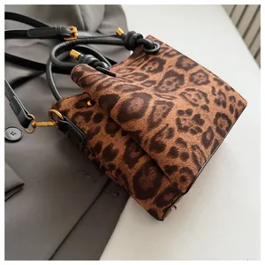 Close-up of leopard print suede crossbody bag with gold hardware and black leather handles