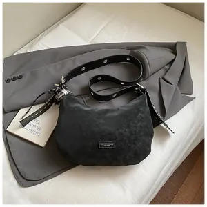 Détail du sac bandoulière demi-lune noir avec œillets argentés et fini rustique