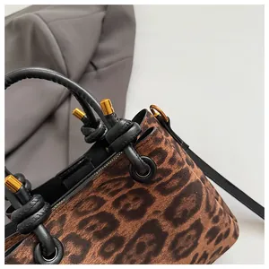 Detailed view of leopard print faux suede fabric with black handles and gold hardware
