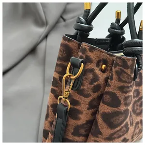 Detail of leopard print suede bag with gold hardware and black leather handle accents